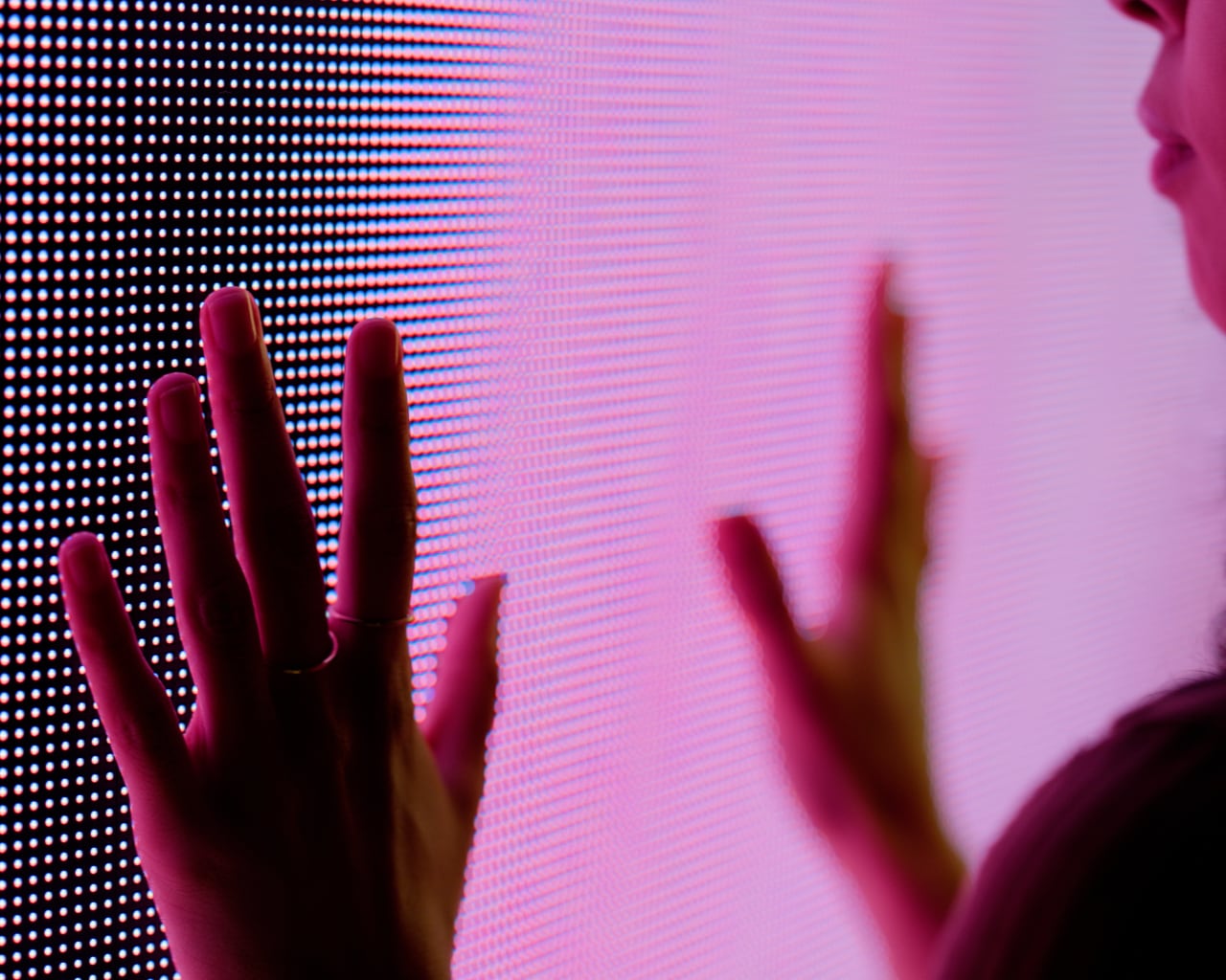 Hände berühren eine LED Wand in Nahaufnahme